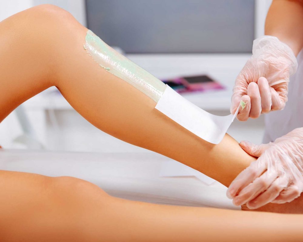 woman receiving leg waxing treatment
